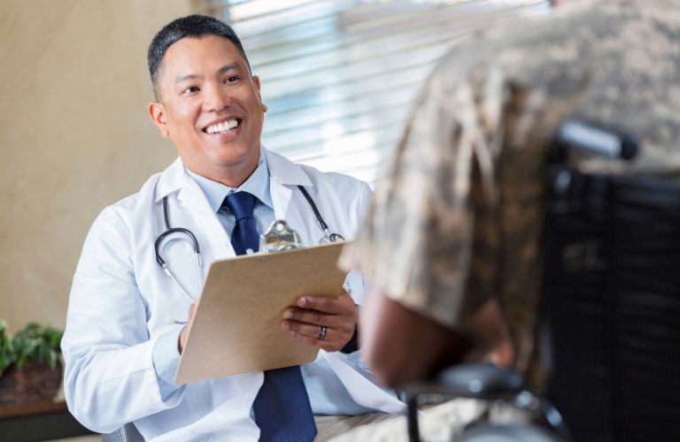 Doctor with Clipboard Speaking with Veteran in Wheelchair