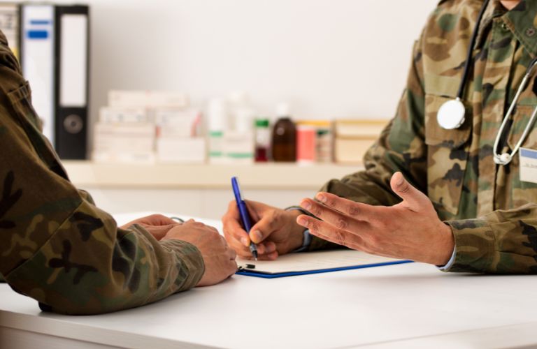 Military Doctor Doing Paperwork with Veteran