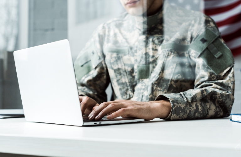soldier in camouflage uniform using laptop
