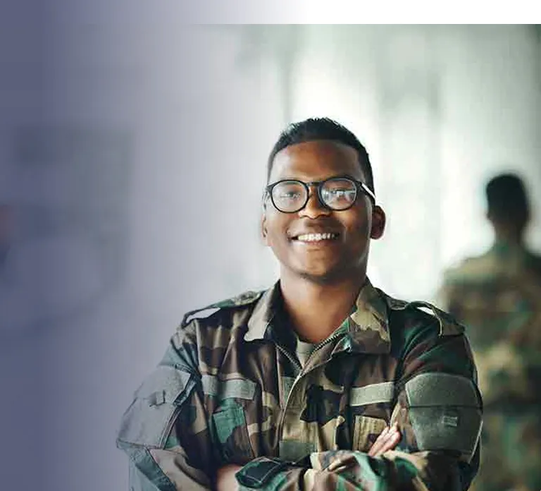 Portrait of a smiling male soldier wearing glasses and camouflage uniform with arms crossed.