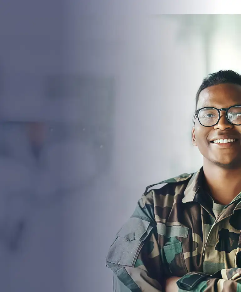 Portrait of a smiling man in camouflage military uniform and glasses, standing with arms crossed.