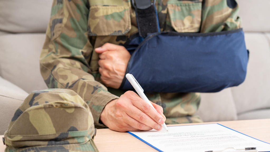 Front view of a handicapped soldier with sling signing contract at office